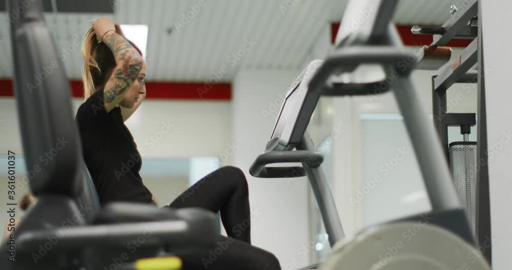 woman exercising with elliptical cross trainer at gym.Side view, slow motion. Woman training at elliptical bike. Woman pedaling at gym woman exercising with elliptical cross trainer at gym.Side view, slow motion. Woman training at elliptical bike. Woman pedaling at gym