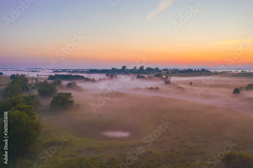 Evening foggy landscape aerial view after rain in a valley of a lake and swamp among meadows and forests. © aapsky