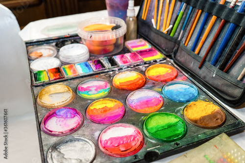Colored paints and brushes for children's makeup. Creative set for applying cosmetics to the face.