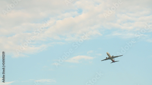 Passenger airplane takes off against the blue sky with clouds.