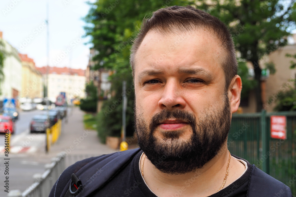 a light-skinned middle-aged man with dark hair and beard stands on an empty street in a city in Europe a light-skinned middle-aged man with dark hair and beard stands on an empty street in a city in Europe