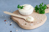 Bowl fresh organic homemade mayonnaise next to wooden spoon with mayo on wood board