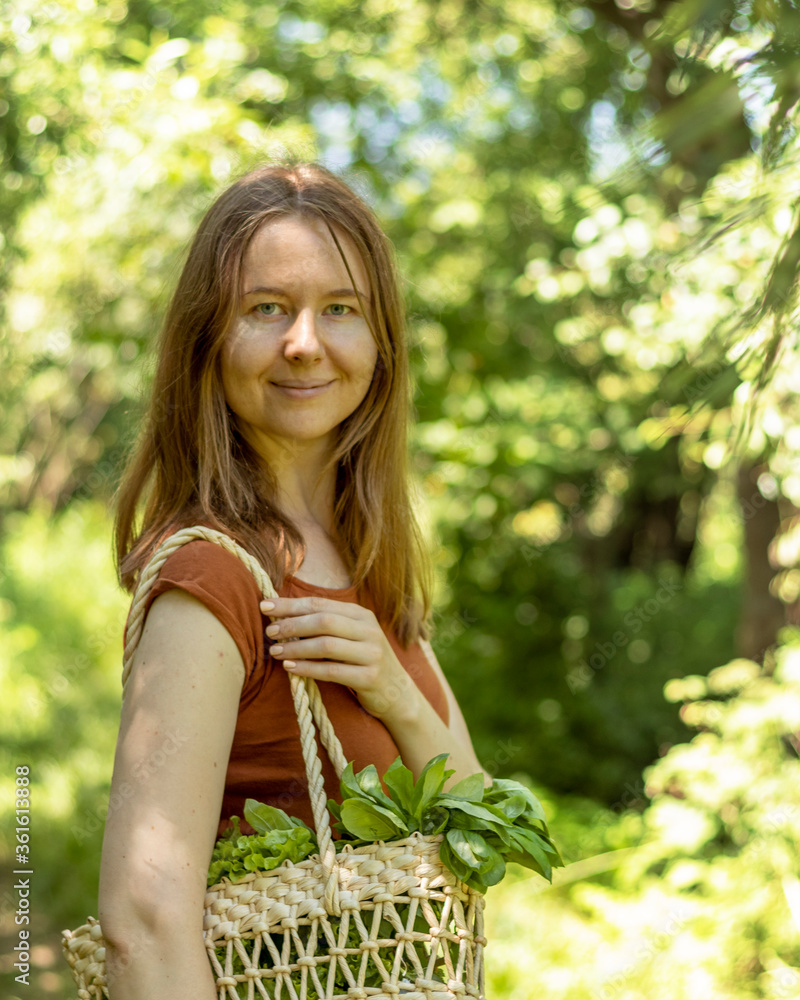 Woman carries in a wicker straw bag fresh greens (salad and basil). Woman carries in a wicker straw bag fresh greens (salad and basil).