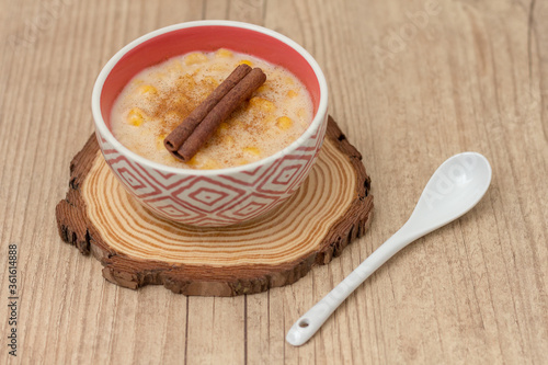 Hominy. Yellow corn with cinnamon in a ceramic bowl. Selective focus. Typical brazilian dessert of june festival in winter - Concept image. photo