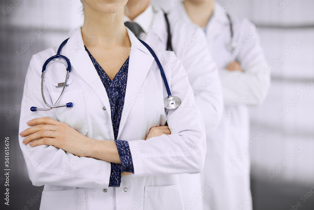 Doctors standing as a team with arms crossed in clinic. Medical help, insurance and medicine concept Doctors standing as a team with arms crossed in clinic. Medical help, insurance and medicine concept