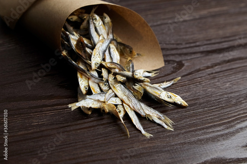 Sun-dried salty small fish. Stockfish on dark wooden background.