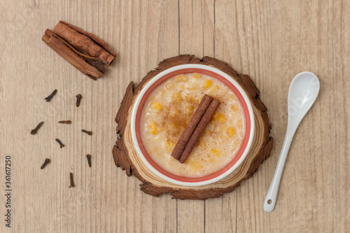 Hominy. Yellow corn with cinnamon in a ceramic bowl. Selective focus. Typical brazilian dessert of june festival in winter - Concept image. photo