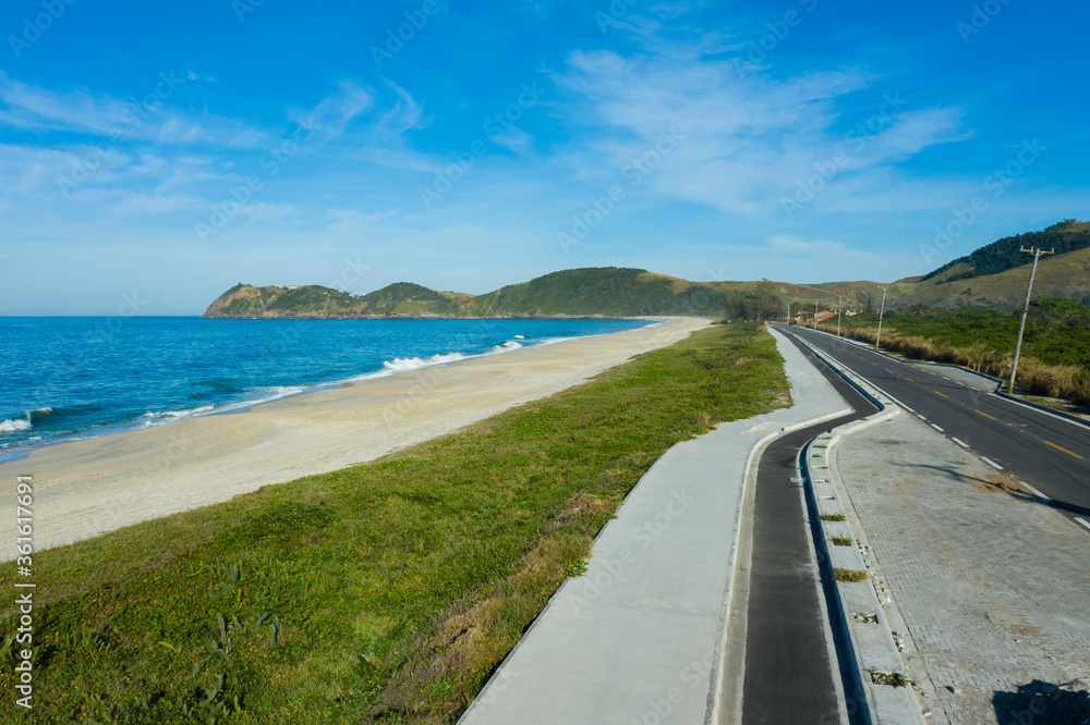 I walk by the sea. Beautiful beach and a road. Long Road to the middle of nowhere. The landscape has taken at Jacone Beach, Rio de Janeiro state, Brazil, South America. 