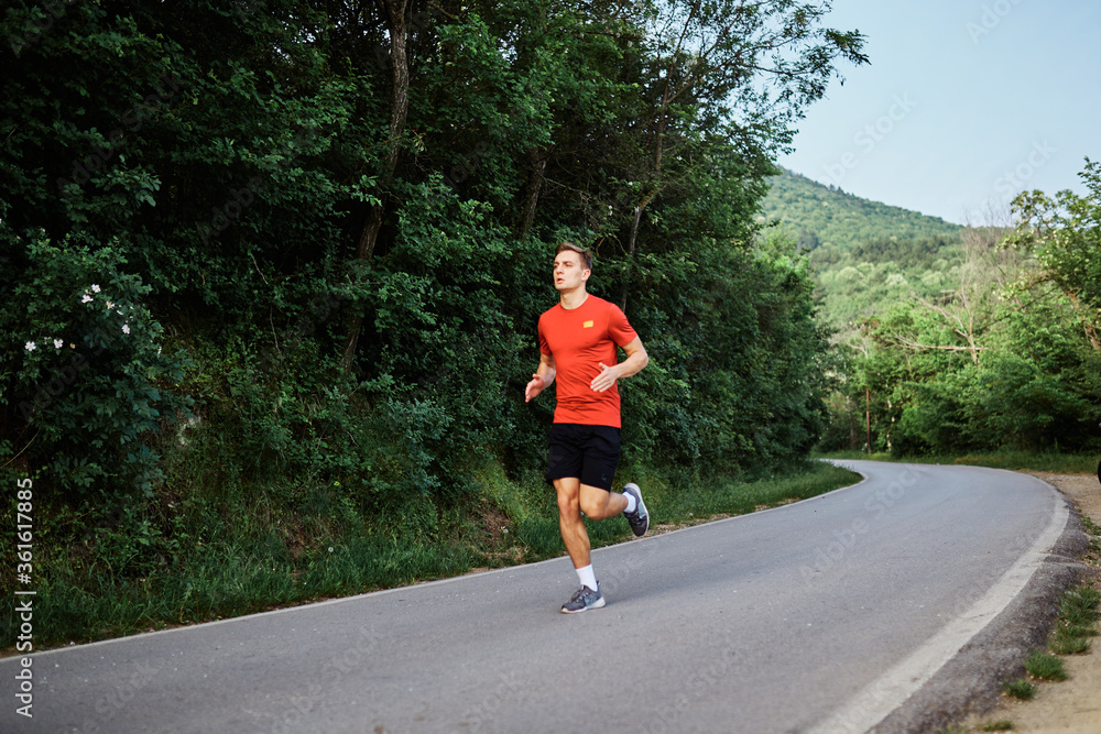 Young man running alone on an empty road Young man running alone on an empty road