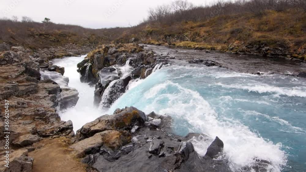 Wide slow motion of water cascading down Midfoss waterfall in Iceland. Wide slow motion of water cascading down Midfoss waterfall in Iceland.