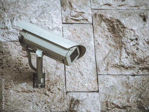 Closeup photo of a surveillance camera on a wall with rough masonry