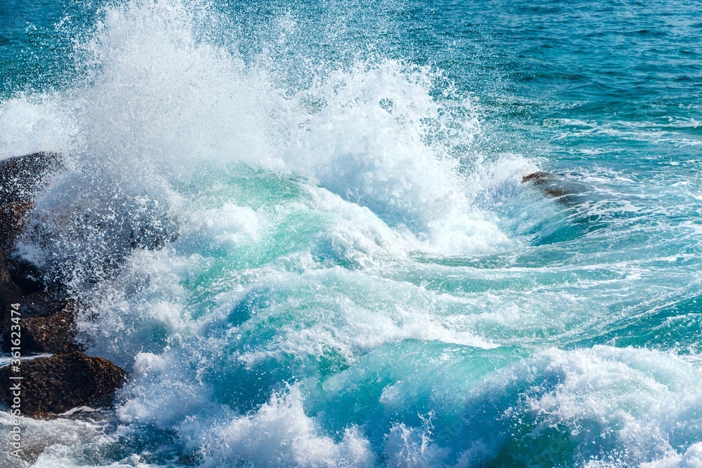 Blue wave in tropical ocean. Turquoise wave barrel crashing on rocks. Close up.