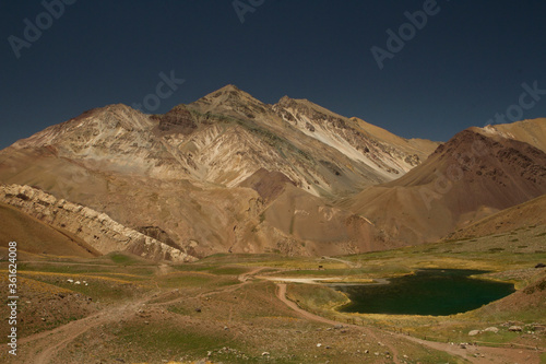 Recreational outdoors activities. Path across the meadow in autumn. Beautiful turquoise color water lake in the mountains.  photo