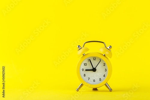Small alarm clock on blue background