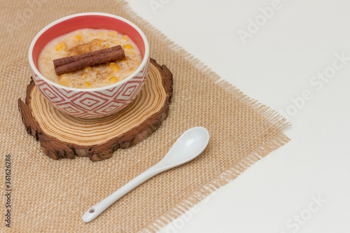 Hominy. Yellow corn with cinnamon in a ceramic bowl. Selective focus. Typical brazilian dessert of june festival in winter - Concept image. photo