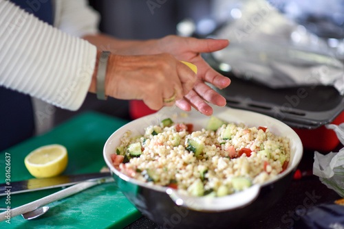 Woman is squeezing a lemon into the homemade vegetarian salad