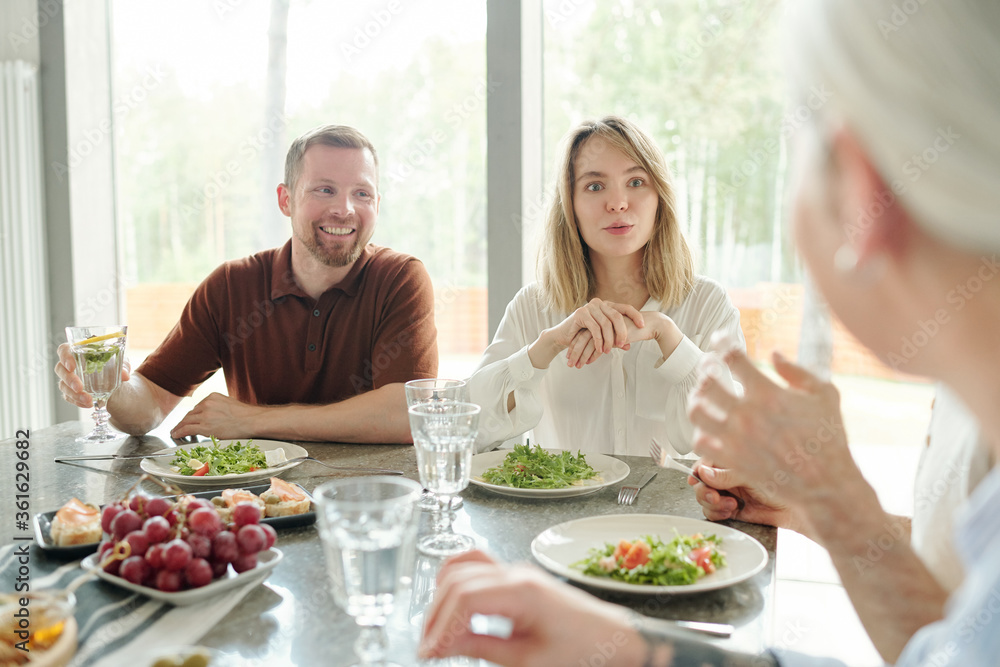 Curious young woman listening with interest to mother while they chatting during family dinner