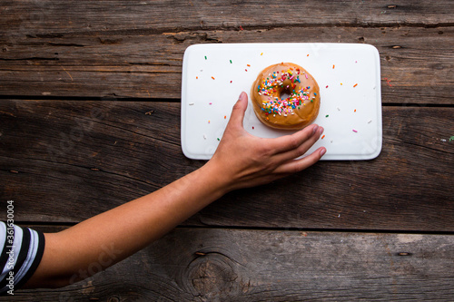 hand reaching for a donut on wooden table