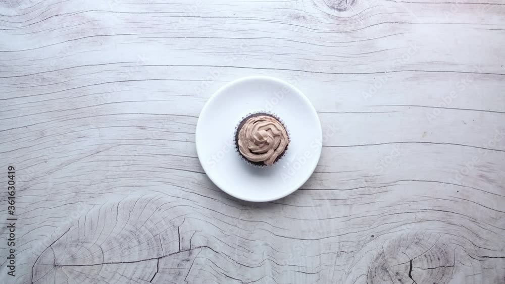 man hand putting chocolate cup cake on a plate 