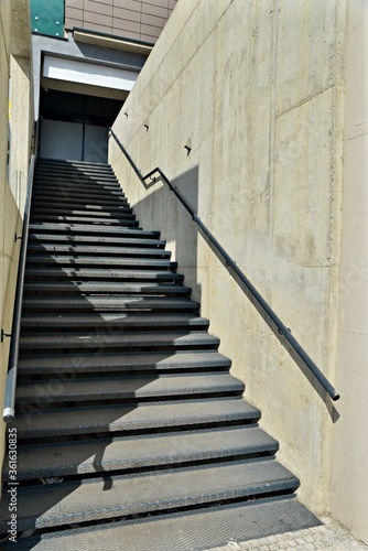 Stairs in the business park. Industrial metal stairs and gray concrete walls.
