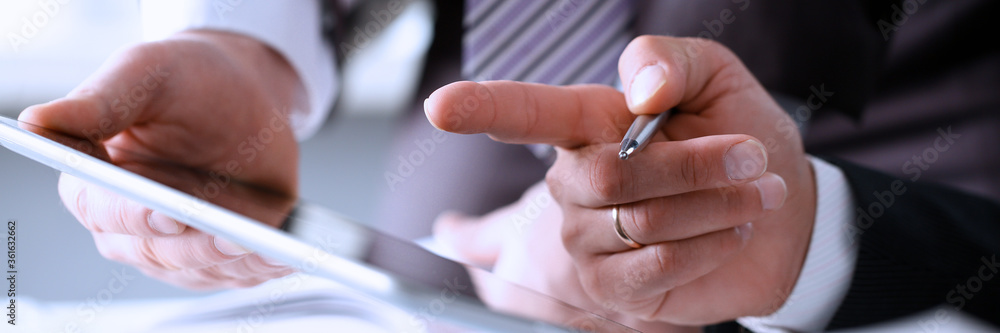 Two businessman are looking and studying statistics on tablet display closeup. Male hand opponent holds pen and points out problem collaboration business coach cooperation partnership palm concept