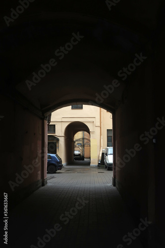 view of the entrance courtyard with a high arch  iron gates and parked cars