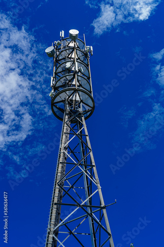 Mobilfunkmast unter blauem HImmel, mit Antennen für Mobilfunk, Digitalfunk, Richtfunk; Freifläche für Text