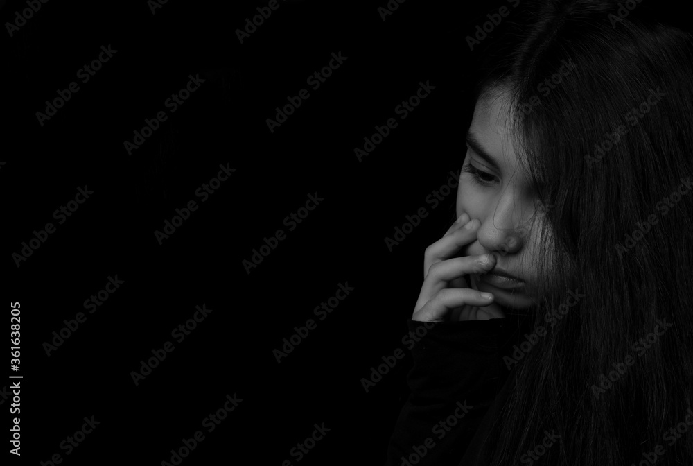 Closeup portrait of serious, sad little girl isolated on black background