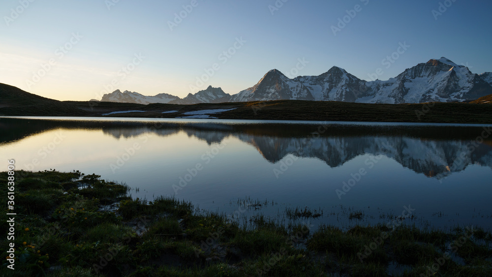 Eiger, Mönch und Jungfrau während Sonnenaufgang mit Spiegelung in Bergsee, Schweiz