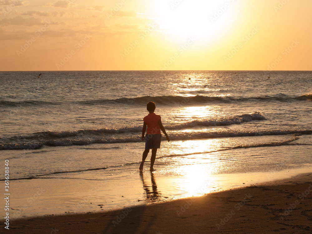 girl backlit from walk on the beach in the sunset