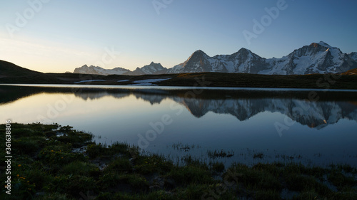 Eiger, Mönch und Jungfrau während Sonnenaufgang mit Spiegelung in Bergsee, Schweiz