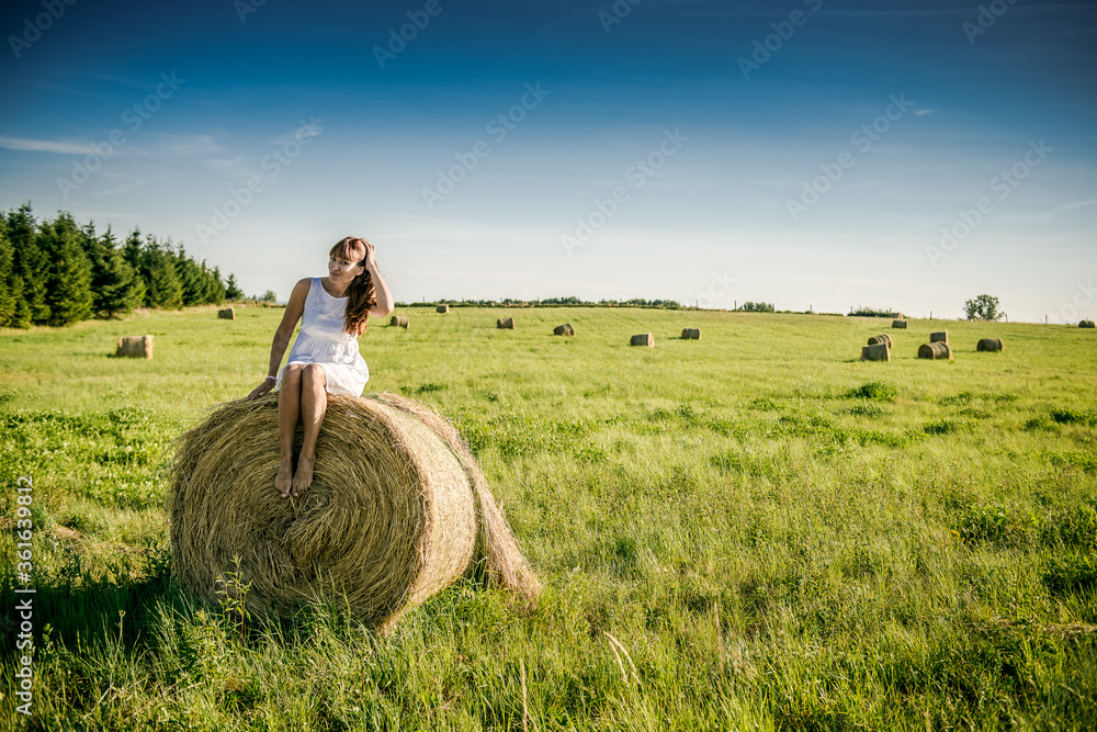 Beautiful girl is resting after work. girl on the field with hay. Woman near a sheaf of hay in a field. Rural life. Holidays in the village Beautiful girl is resting after work. girl on the field with hay. Woman near a sheaf of hay in a field. Rural life. Holidays in the village