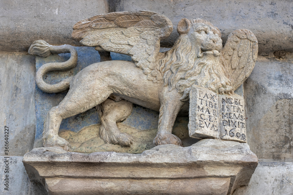 Sculpture of a winged lion on the facade of an old house. Symbol of medieval Venice.