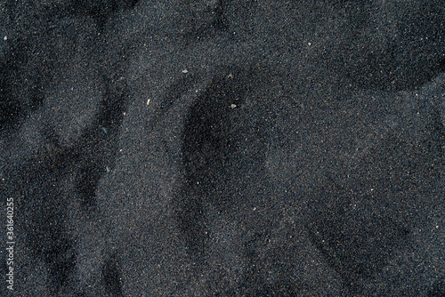 Black sand beach macro photography. Silky black beach texture. Minimalistic black background. Tenerife voulcanic sandy shore.