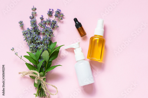 Organic cosmetic products and bouquet of fresh aromatic lavender on light pink background top view. Skin care concept.