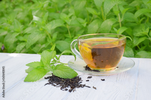 Cup of fragrant mint black tea with honey on a wooden background