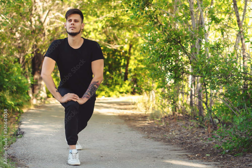 Bearded young man exercising in park before jogging. Copy space