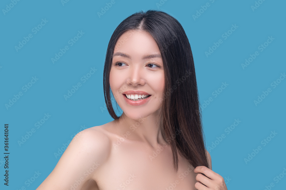 Smiling dark-haired model having a shooting on a blue background Smiling dark-haired model having a shooting on a blue background