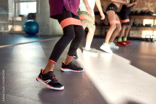 Close up of legs of kids working out using resistance band in gym. Sport, healthy lifestyle, physical education concept