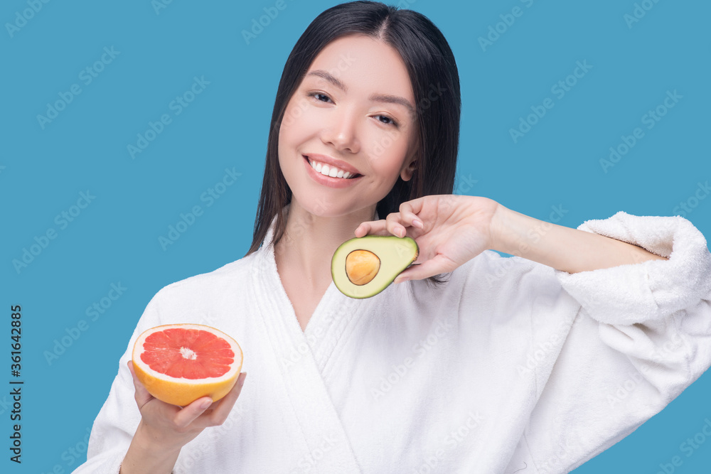 Smiling woman holding an avocado and grapefruit Smiling woman holding an avocado and grapefruit