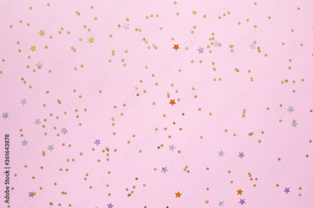 Golden stars shaped confetti glitter on pink background.