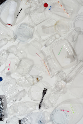 Flatlay composition with used plastic bottles, containers, forks, spoons, egg packaging, caps over white background photo