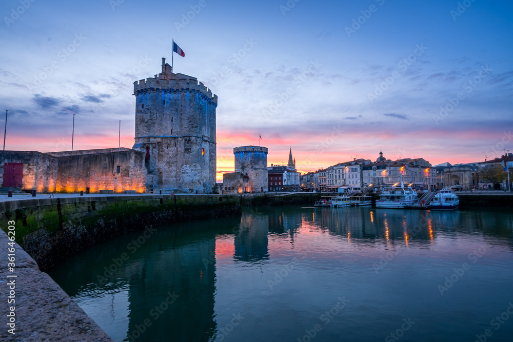 The old harbor of La Rochelle at sunset with its famous old towers. beautiful orange sky