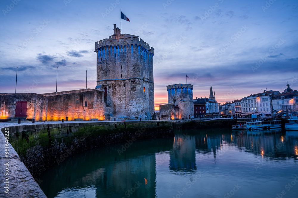 The old harbor of La Rochelle at sunset with its famous old towers. beautiful orange sky