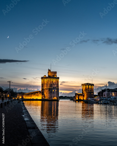 the old harbor of La Rochelle at blue hour with its famous old towers. moon in the sky. Portrait format