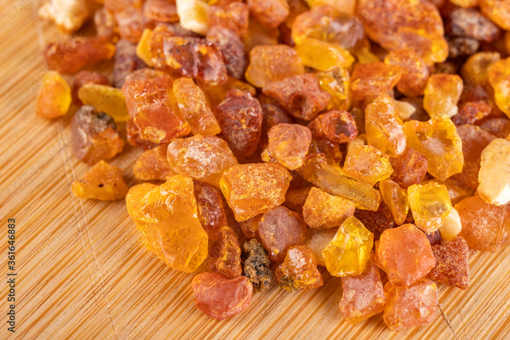 Raw small pieces of amber arranged on a wooden board. Precious pieces of old Baltic resin. Dark background. Raw small pieces of amber arranged on a wooden board. Precious pieces of old Baltic resin. Dark background.