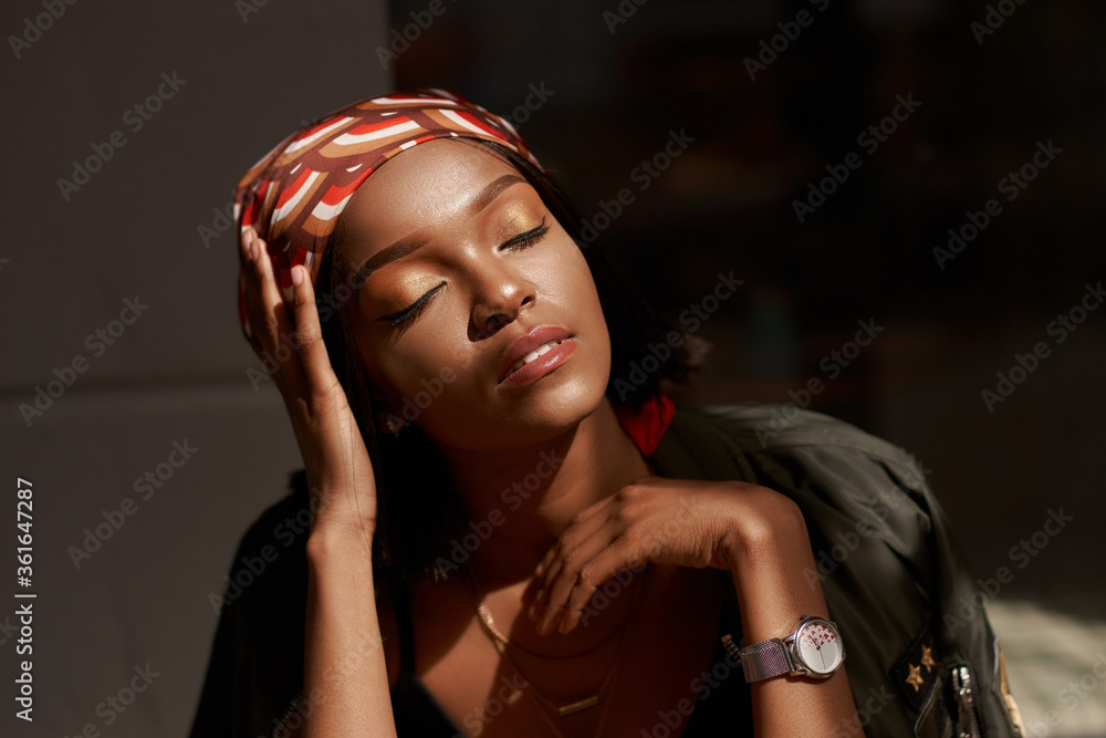 Lifestyle outdoor portrait of beautiful pretty stylish sensual african woman wearing jeans and shirt sitting and relaxing. - obrazy, fototapety, plakaty 