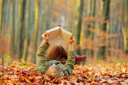 Child reading a book, colorful autumn in the park. Hobbies and rest. photo