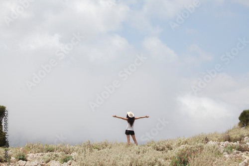 Portrait of a young woman in a mountainous landscape of the island of Majorca during the summer holidays. The woman is hiking on top of the peaks and has views of the sky and clouds.