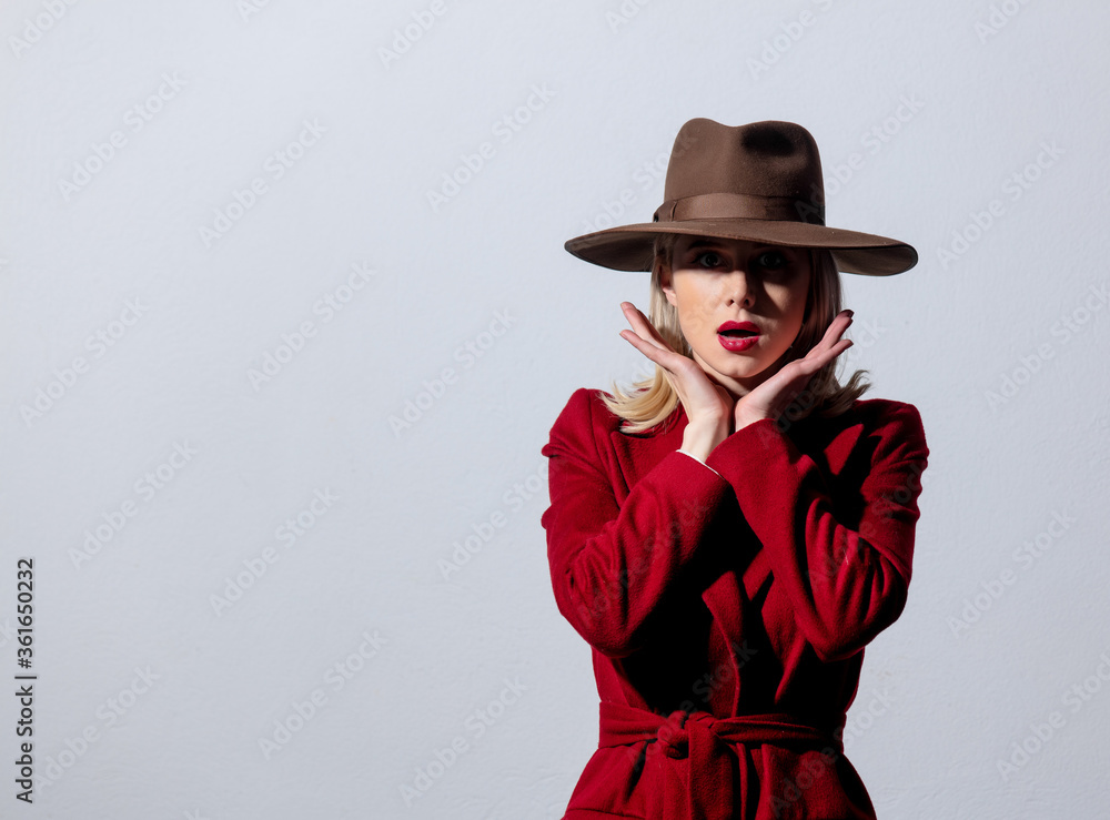 Fototapeta premium Blonde girl in red coat and vintage hat on grey background